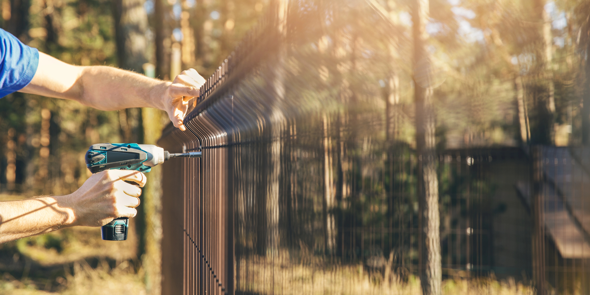 Fencing - worker installing metal wire mesh fence panel