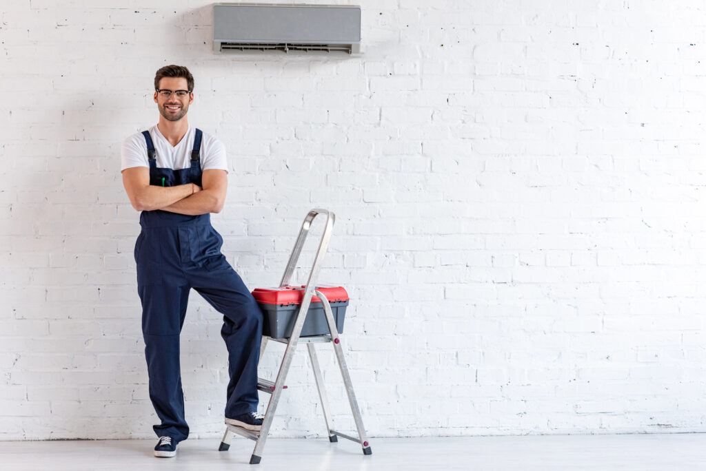 Smiling repairman standing under air conditioner 