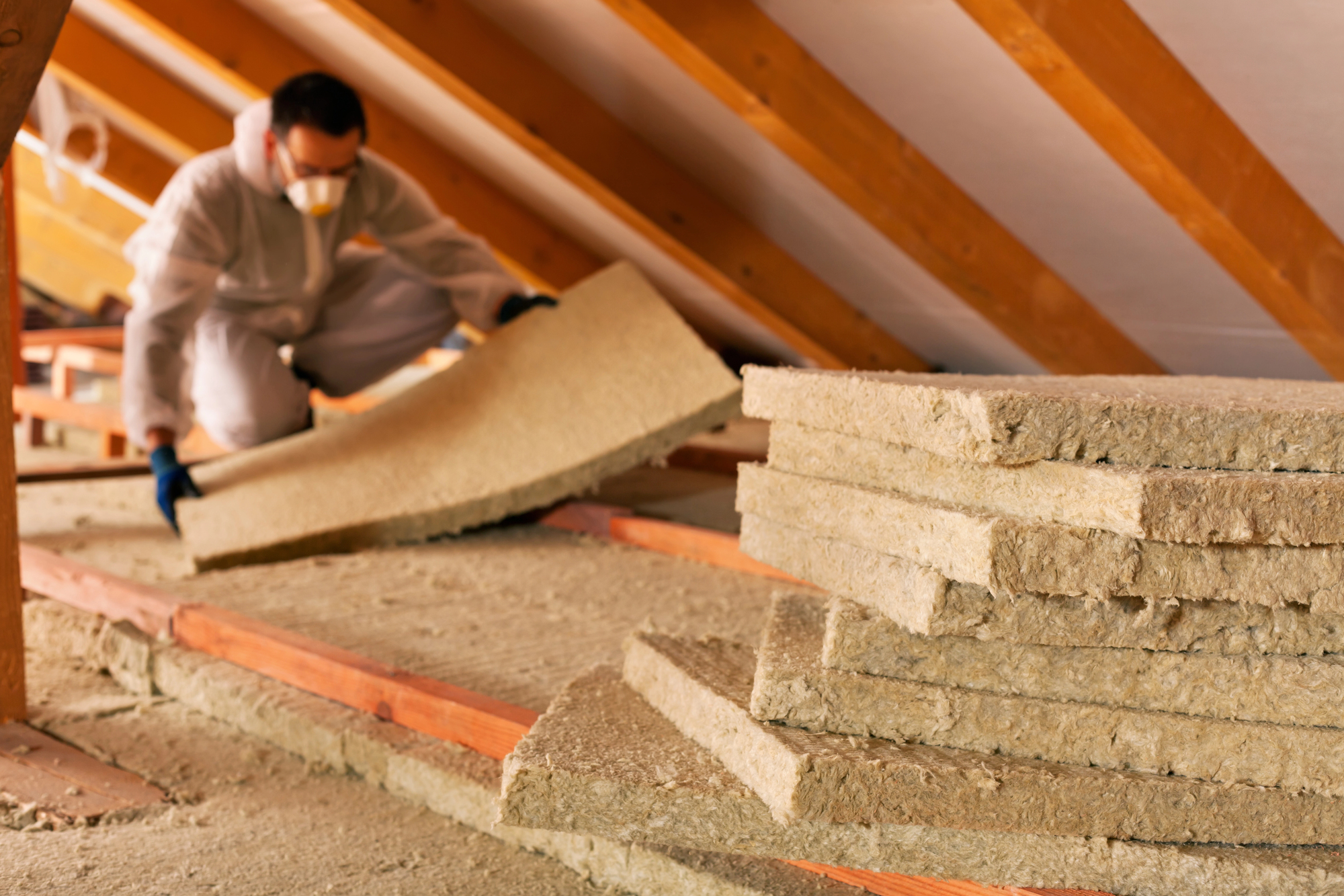 Man laying thermal insulation layer under the roof