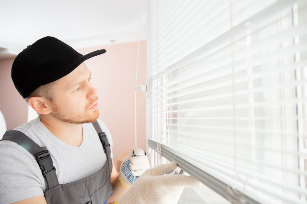 Construction worker man install blinds on plastic white uPVC window