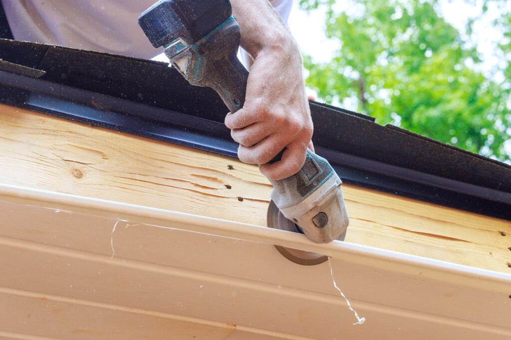 Cutting off established vinyl soffit panels facade ceiling of new house to a given size