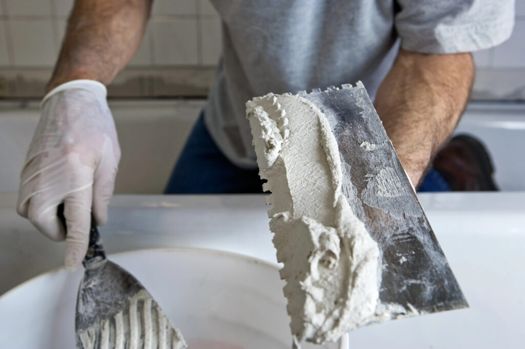 Man Working with Trowel and Mortar TIling a Bathroom Wall